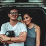 woman leaning on man's shoulder beside car during daytime